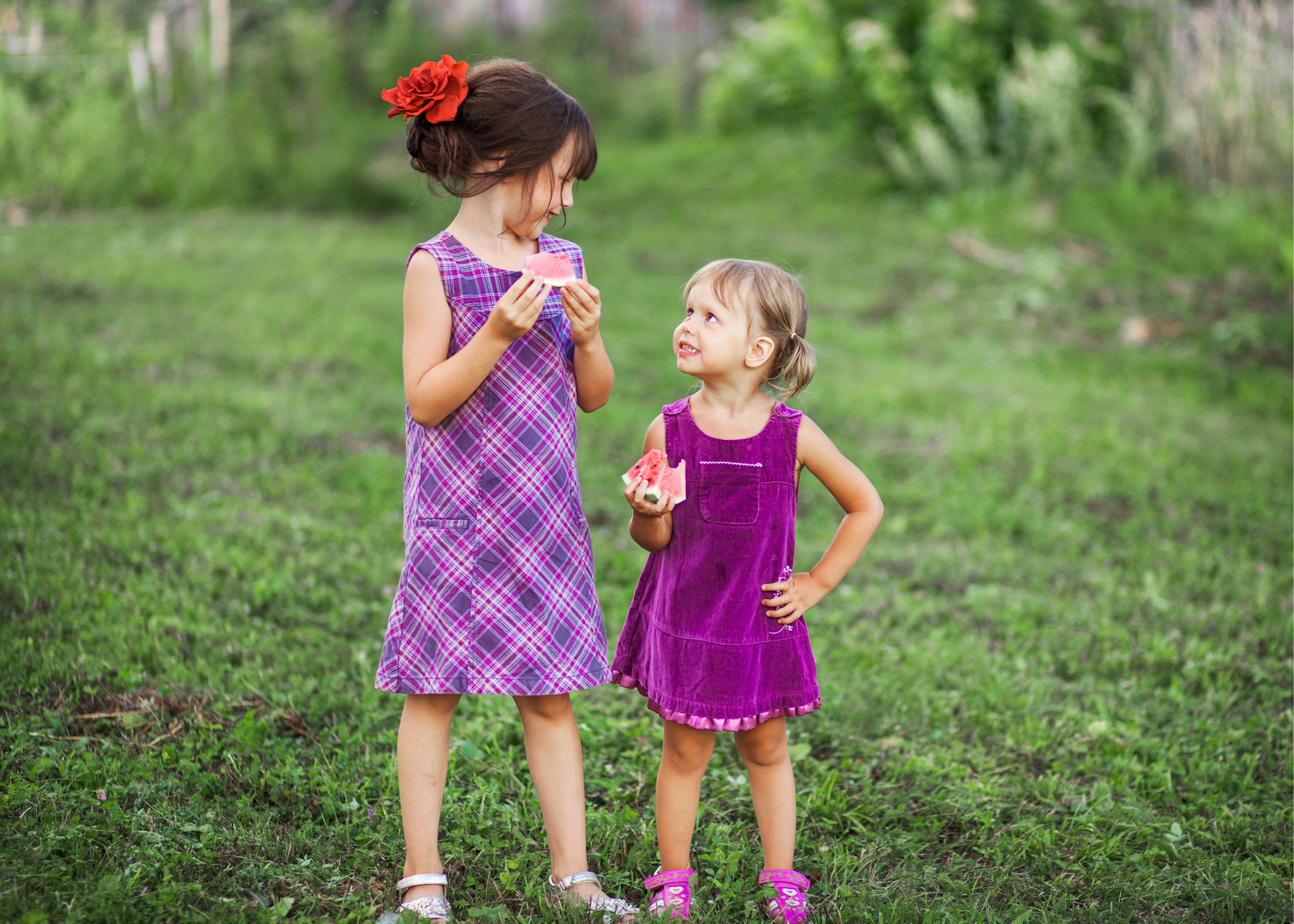 Sisters eating watermelon on grass